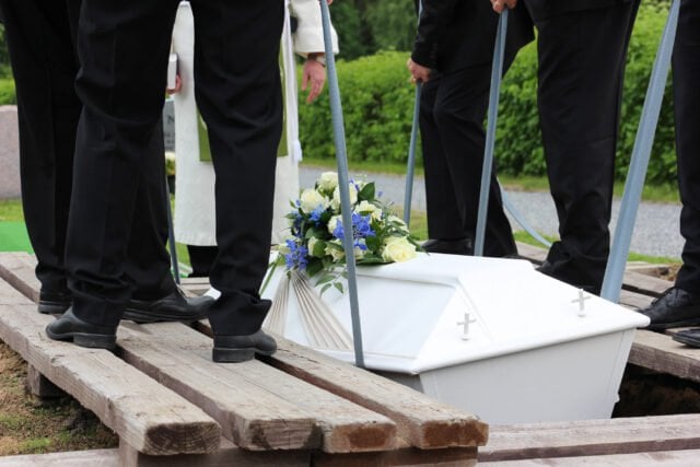 Sargträger, die den Sarg auf einer Beerdigung niederlegen